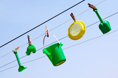 Low angle view of multi colored clothespins hanging against clear sky