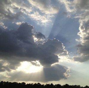 Low angle view of sun shining through clouds