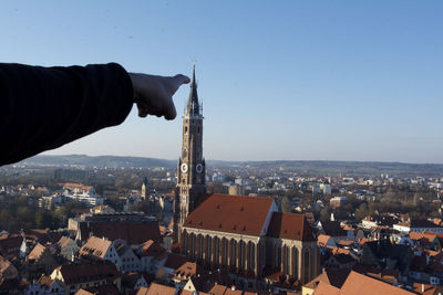 Midsection of man holding townscape against sky in city