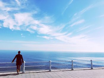 Rear view of man standing on bridge against sky