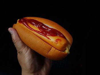 Close-up of hand holding apple against black background