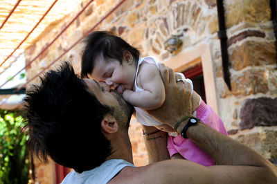 Father playing with daughter while standing in yard