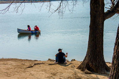 Man sitting near people on boat in lake