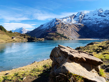 Scenic view of lake by snowcapped mountains against sky