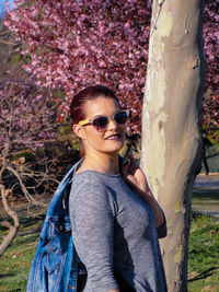 Portrait of young woman wearing sunglasses while standing in forest