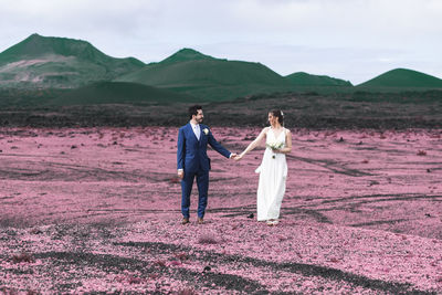 Front view of a man and woman standing together on a volcanic landscape 