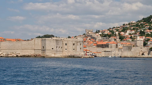 Buildings by sea against sky in city