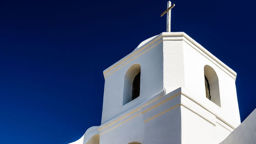 Low angle view of bell tower against clear blue sky