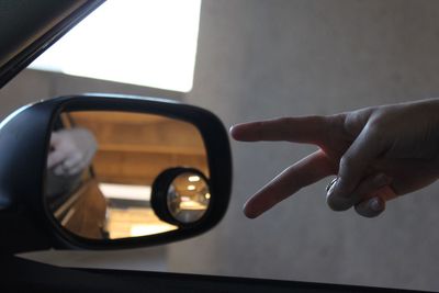 Close-up of hand on side-view mirror of car