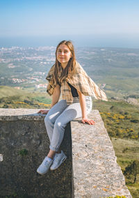 Portrait of young woman standing on mountain against sky