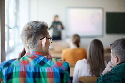 Rear view of couple sitting in classroom