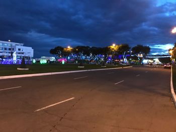 Illuminated city street against sky at night