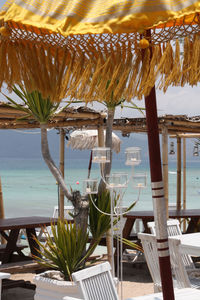 Close-up of table and chairs at beach against sky