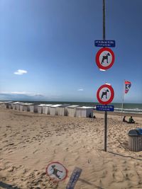 Information sign on beach against sky