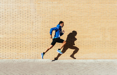 Full length of man running on footpath