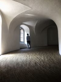 Rear view of man walking in corridor of building