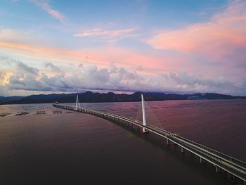 Bridge over sea against sky during sunset