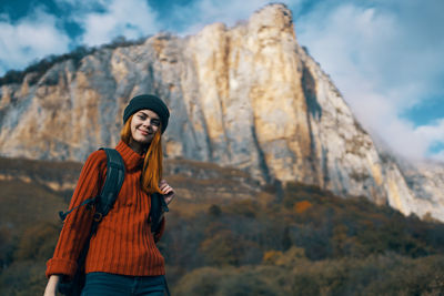 Portrait of smiling young woman standing against sky