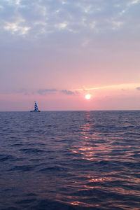 Boat sailing in sea against sky during sunset