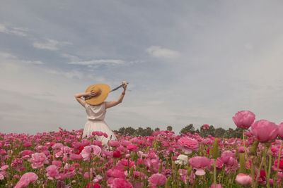 Woman in hat in field of pink flowers