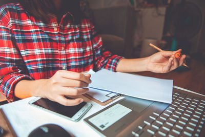 Midsection of woman using smart phone on table