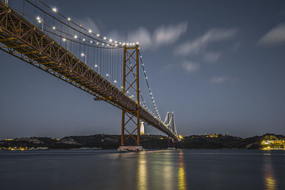 Low angle view of 25th of april bridge over river tejo in lisbon against sky 