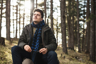 Thoughtful man sitting at forest