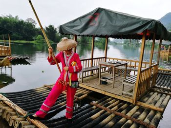 Woman standing on wooden raft on river