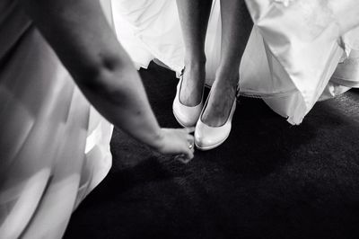 Friend adjusting high heel on bride