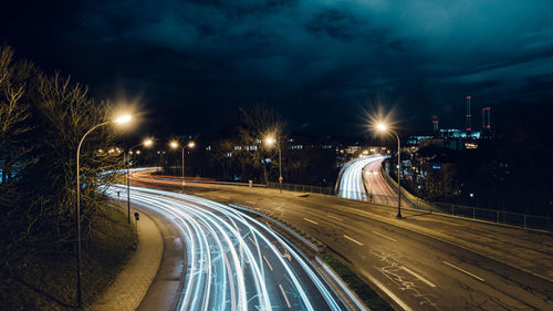 Light trails on road in city against sky at night