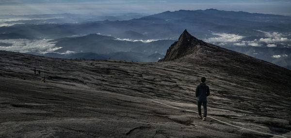 Rear view of man standing on land against sky