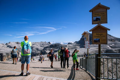 People walking on mountain road against blue sky