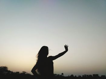 Silhouette woman gesturing while standing against clear sky
