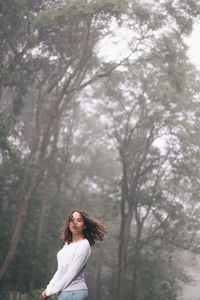 Woman standing by tree against sky