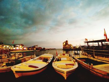 Boats moored at harbor against sky during sunset
