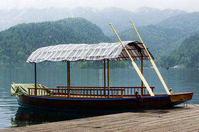 Boat moored on lakeshore against mountains