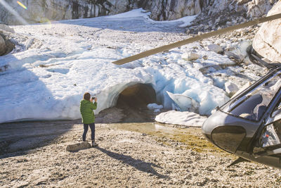 Young woman taking photo of ice cave while on helicopter tour.