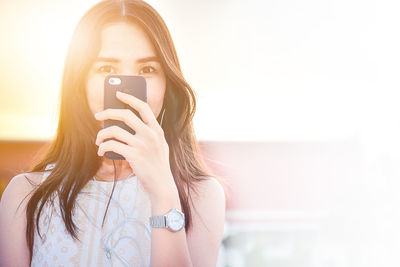 Portrait of woman photographing with mobile phone