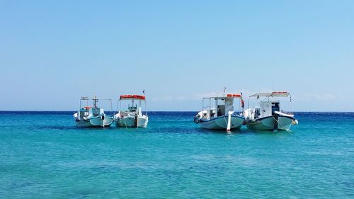 Boats in sea against clear sky