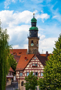 Clock tower amidst buildings in city against sky