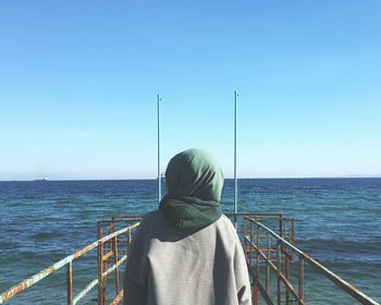 Rear view of woman looking at sea against clear sky