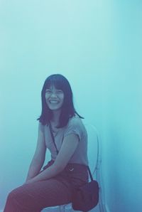 Low section of woman sitting against blue background