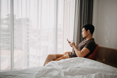 Young woman using laptop while lying on bed at home