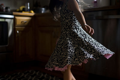 Midsection of girl spinning around at home in darkroom