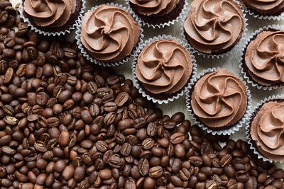 High angle view of roasted coffee beans and cupcakes on table