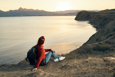 Man sitting on rock at shore