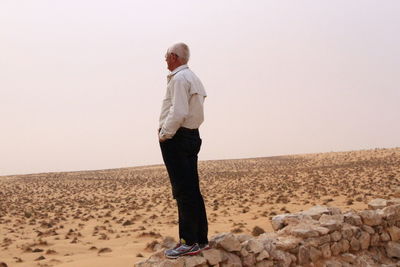 Full length of man standing on sand at beach against clear sky