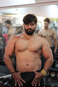 Portrait of shirtless young man standing at gym