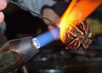 Cropped image of woman making glass with flaming torch in factory