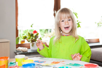 Portrait of girl sitting on table at home